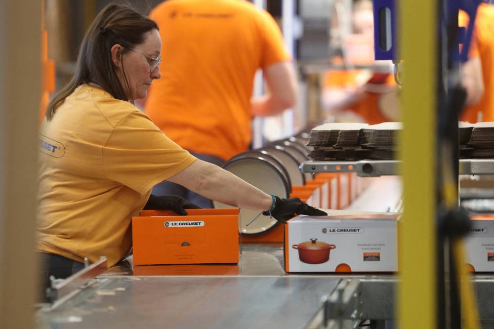 An employee packs enameled cast iron casseroles on a packaging line of Le Creuset foundry during a press visit to mark the brand's 100th anniversary in Fresnoy-le-Grand, on April 29, 2025. - (Photo by FRANCOIS LO PRESTI / AFP)