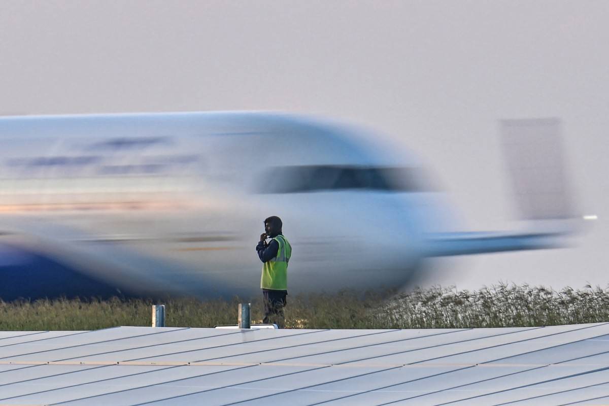 A ground staff looks on as an Indigo aircraft prepares to take off at the Kempegowda International Airport in Bengaluru on Dec 29, 2024. - (Photo by IDREES MOHAMMED / AFP)