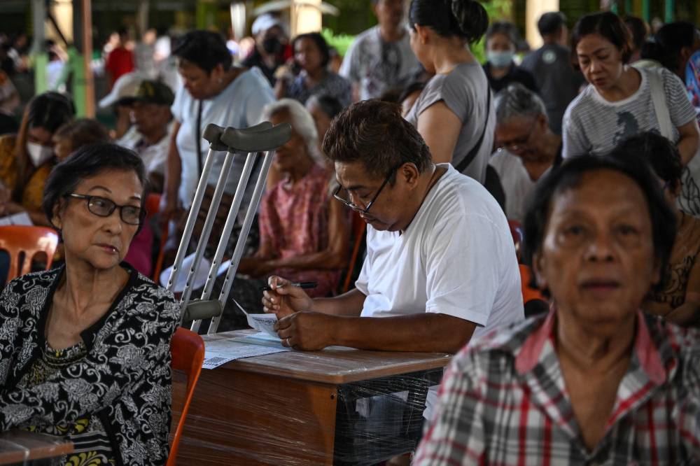 A man (C) votes at a polling station during mid-term elections in Manila on May 12, 2025. - (Photo by JAM STA ROSA / AFP)