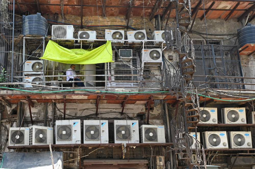 In this photograph taken on May 2, 2024, a man sits in a balcony amid air conditioning units installed on the facade of a building in New Delhi. (Photo by Sajjad HUSSAIN/AFP)