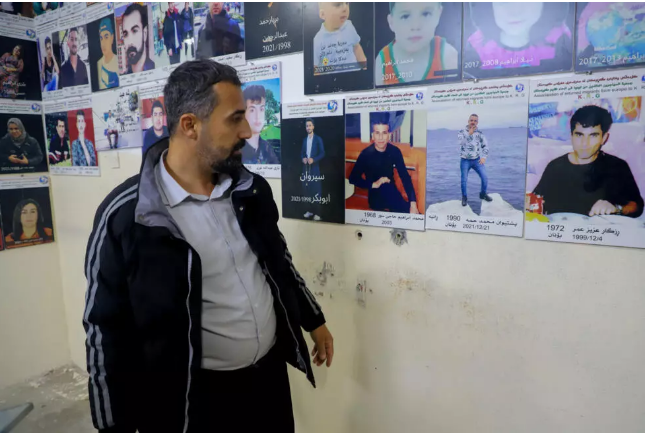 Hardi Ahmed with pictures of people who lost their lives trying to reach Europe. - Shwan MOHAMMED/AFP