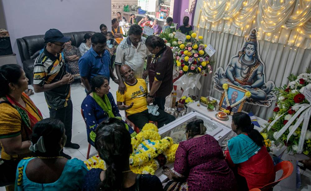 The late K. Sugunanathan's father (second from right) and his wife, W. Helen Tracy (third from left), were comforted by friends and family as they pay their last respects at Bandar Baru Lahat Mines today. - Bernama photo
