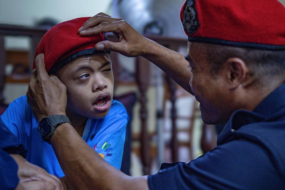 Corporal Mohd Shaukar Ishak, 36, Federal Reserve Unit (FRU) personnel, placed the FRU beret belonging to the late Sergeant Mohd Roslan Abd Rahim on his special needs son, Muhd Raqin Najmi, 13, at their home in Taman Meru yesterday (May 15). Raqin is the eldest child of Sergeant Mohd Roslan, who tragically died in an accident in Teluk Intan last Tuesday. Mohd Roslan was one of nine members of the Federal Reserve Unit confirmed dead after being involved in a collision between the FRU truck carrying 18 personnel including the driver, and a lorry loaded with stones. - Bernama photo 