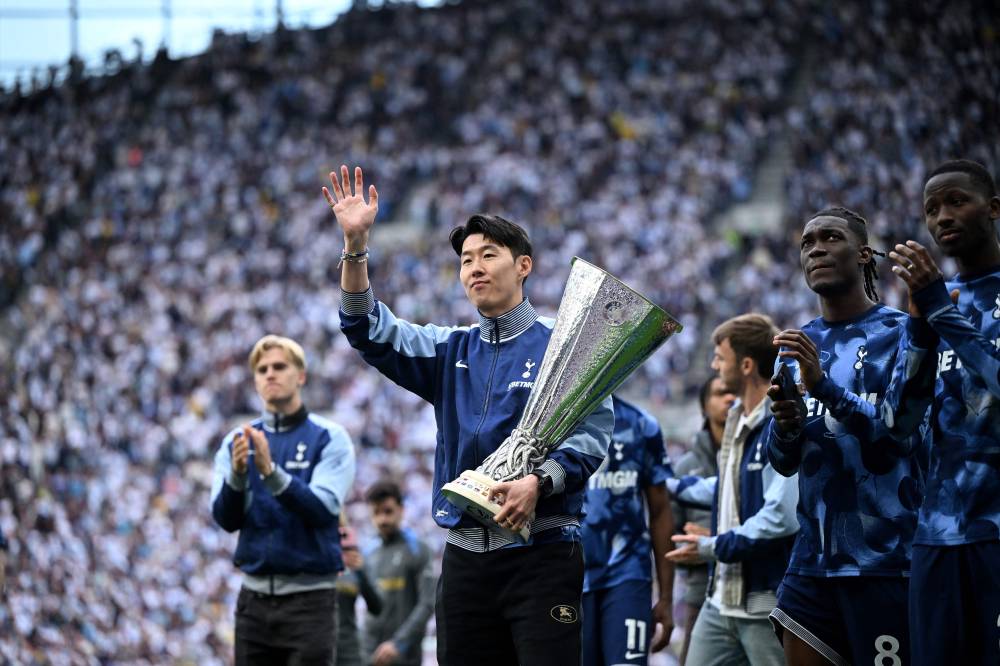 Tottenham Hotspur's South Korean forward #07 Son Heung-Min carries the Europa League trophy, following their mid-week win in the Europa League Final on May 21, as he and the team display it for fans following the English Premier League football match between Tottenham Hotspur and Brighton and Hove Albion at the Tottenham Hotspur Stadium in London, on May 25, 2025. (Photo by JUSTIN TALLIS/AFP)
