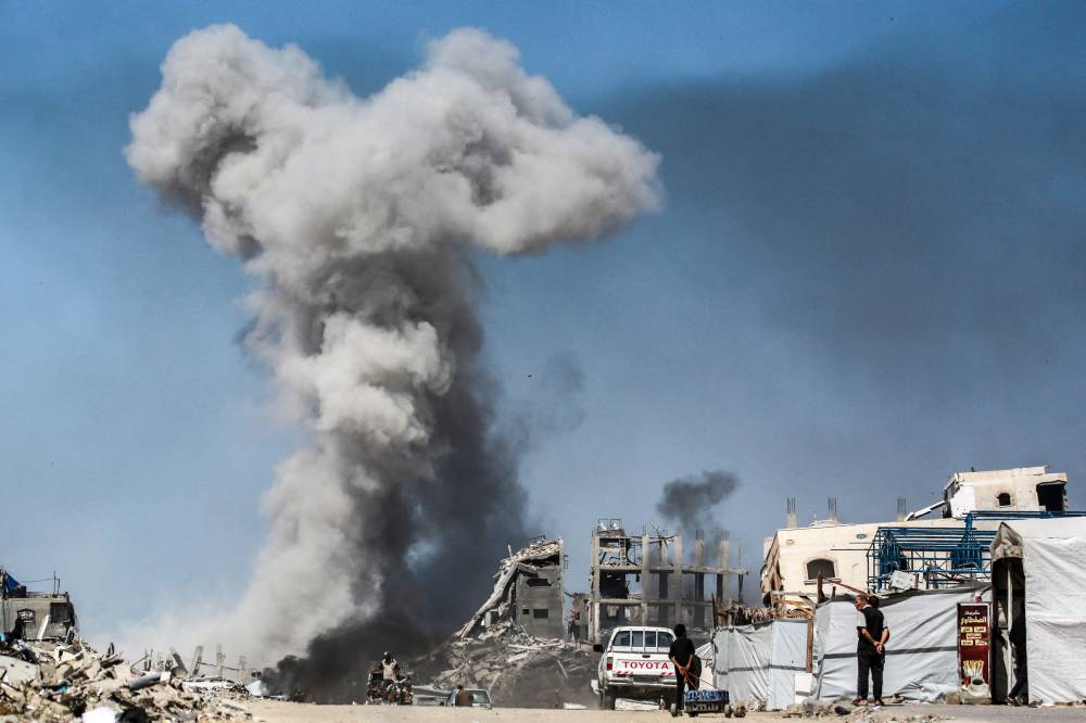 People watch as smoke billows following an Israeli strike in Jabalia, in the northern Gaza Strip on May 25, 2025. Rescuers in Gaza said 22 people were killed and dozens more wounded in Israeli air strikes across the Palestinian territory. - (Photo by BASHAR TALEB / AFP)