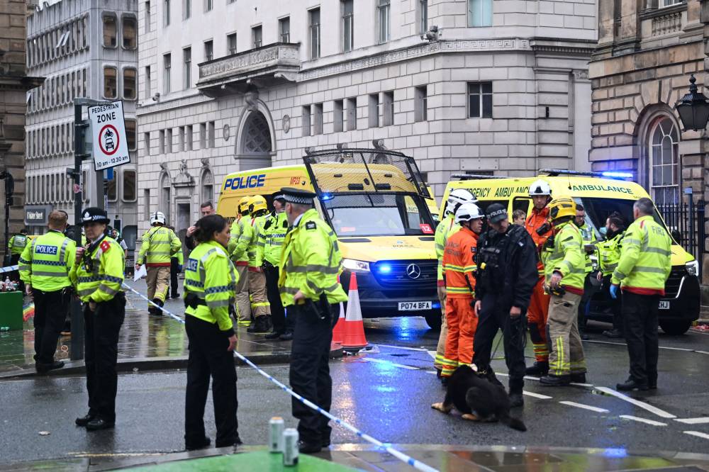 Police officers stand guard by the Liverpool Town Hall following an incident in Water Street (rear), on the sidelines of an open-top bus victory parade for Liverpool's Premier League title win, in Liverpool, north-west England on May 26, 2025. A car collided with a number of pedestrians in Liverpool, northern England, on May 26 evening during Liverpool FC's Premier League victory parade, police said. Police said they were contacted shortly after 6pm (1700 GMT) ‘following reports of a collision between a car and a number of pedestrians’ in the city centre. One man has been arrested, according to the police, who did not say whether there were any casualties. (Photo by Paul ELLIS / AFP)