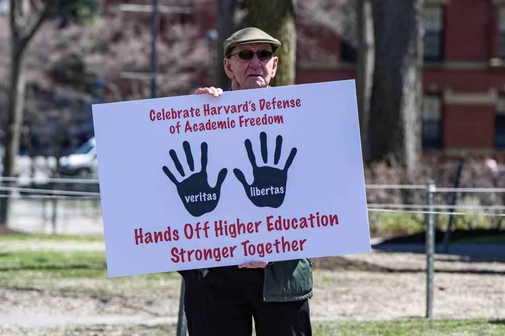 A Harvard Faculty member holds a sign as he exits Harvard Yard after a rally was held against US President Donald Trump’s attacks on Harvard University at Harvard University in Cambridge, Massachusetts on April 17, 2025. - (Photo by Joseph Prezioso / AFP)