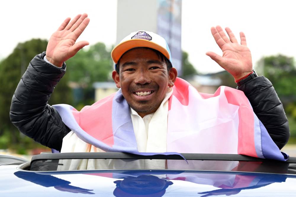 Nepali climber Tashi Gyalzen Sherpa gestures as he arrives at Tribhuvan International Airport in Kathmandu on May 27, 2025, after he made a record-breaking four summits of Everest in fifteen days. (Photo by PRAKASH MATHEMA / AFP)