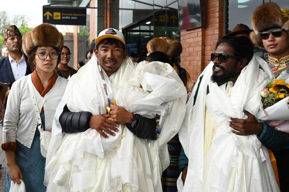 Nepali climber Tashi Gyalzen Sherpa (C) arrives at Tribhuvan International Airport in Kathmandu on May 27, 2025, after he made a record-breaking four summits of Everest in fifteen days. Nepal has issued more than 1,100 permits for mountaineers this season, including 458 for Everest, earning more than $5 million in royalties. The country is home to eight of the world's 10 highest peaks and welcomes hundreds of adventurers each spring, when temperatures are warmer and winds typically calmer. (Photo by PRAKASH MATHEMA / AFP)