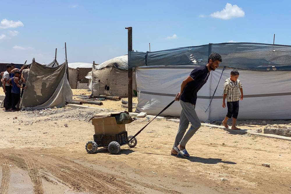 A displaced Palestinian man pulls a cart holding a parcel as he returns from an aid distribution centre in Khan Yunis in the southern Gaza Strip on May 28, 2025. - (Photo by AFP)