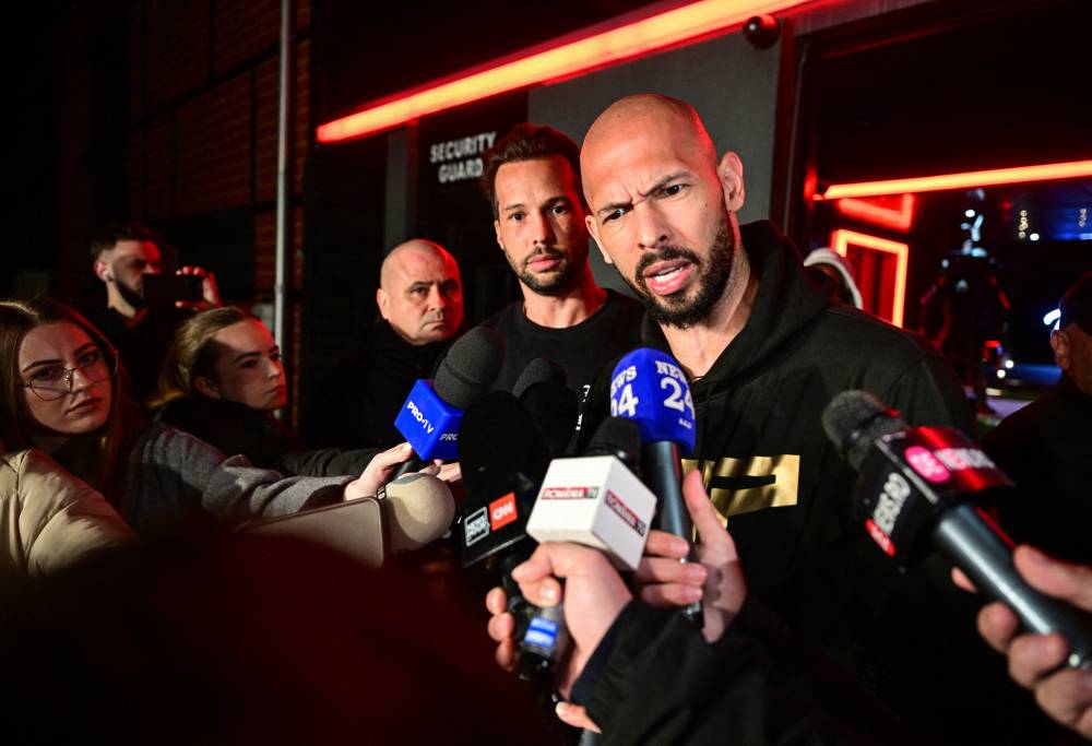 Andrew Tate (R) and his brother Tristan speak to the media as they arrive in Romania back from US, in Bucharest March 22, 2025. - (Photo by DANIEL MIHAILESCU / AFP)