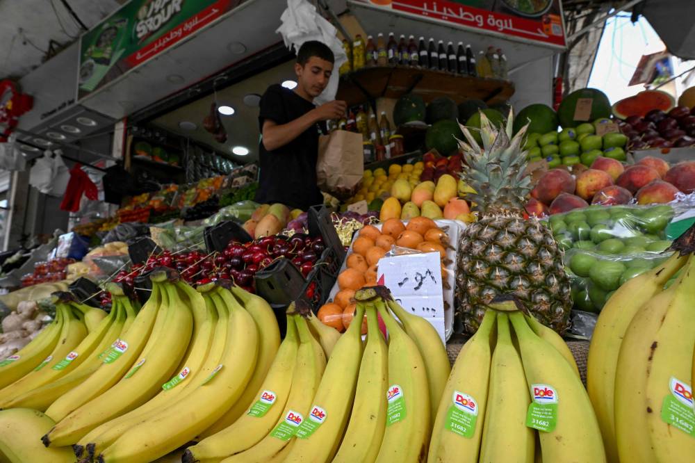 A boy walks past a produce merchant's stall selling previously unavailable items during the reign of deposed president Bashar al-Assa, such as kiwi, mango, and pineapple,in the Shalaan Market of Damascus on May 26, 2025. (Photo by LOUAI BESHARA / AFP)