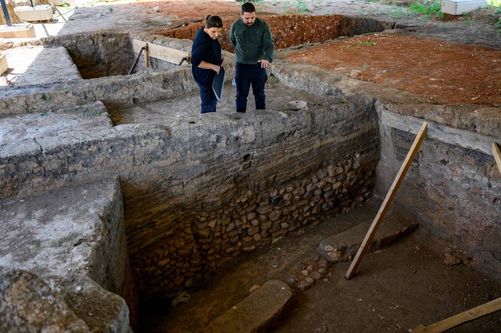 Archeologists Murat Turkteki (R) and Deniz Sari look at an ancient house at the Kulluoba excavation site, in Eskisehir province, in central Turkey, on May 23, 2025. A 5,000-year-old loaf of bread was discovered in September 2024 by archaeologists in Eskisehir province, central Turkey. Since May 22, the municipality has been reproducing it using the original recipe and plans to revive the cultivation of ancient wheat, which is better suited to drought. (Photo by Yasin AKGUL / AFP)