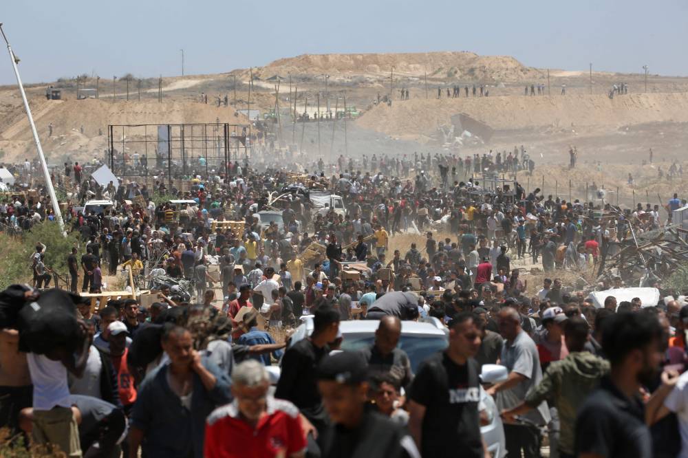 Displaced Palestinians carrying relief supplies return from an aid distribution centre in the central Gaza Strip on May 29, 2025. - (Photo by EYAD BABA / AFP)