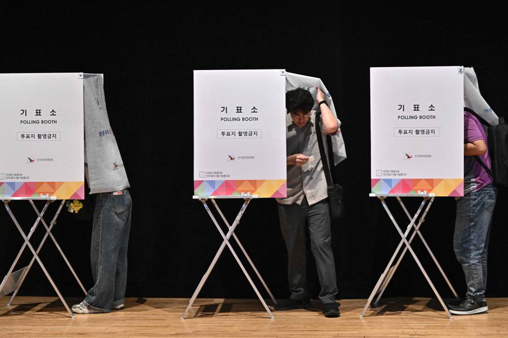 A person steps out of a booth at a polling station during early voting for the presidential election in Seoul on May 29, 2025. (Photo by Pedro PARDO / AFP)