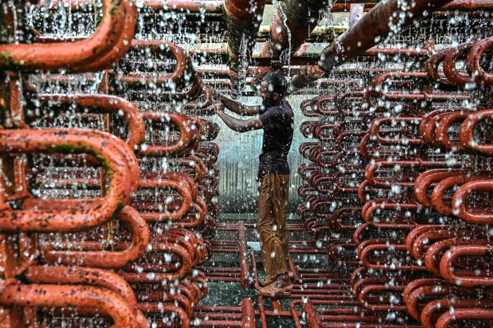 A worker cleans the lines of a cooling tower at an ice factory on a hot summer day in Karachi on May 29, 2025. (Photo by Asif HASSAN / AFP)