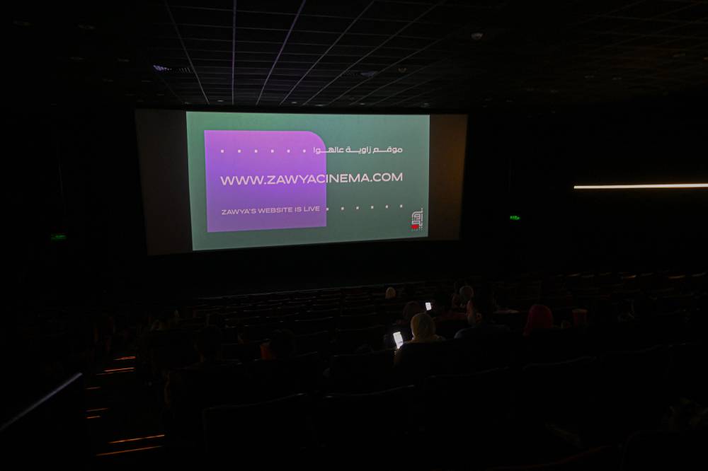 People wait for a movie to start at the Zawya cinema in downtown Cairo on May 1, 2025. In the heart of Cairo, a small cinema has for over a decade offered a unique space for independent film in a country whose industry is largely dominated by commercial considerations (Photo by Khaled DESOUKI / AFP)
