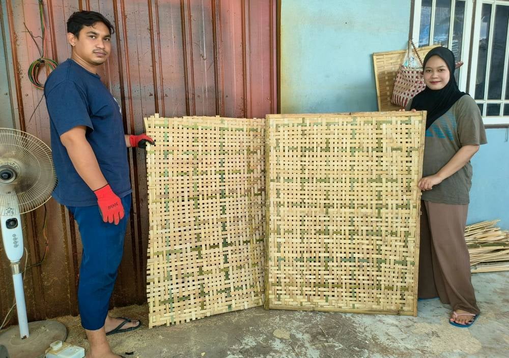 Diniey Iqbal Che Kar, 30 (left), and Nuur Faraiin Mat Rowi, 26 (right), showcasing their handmade weavings at Kampung Talak. - Bernama photo