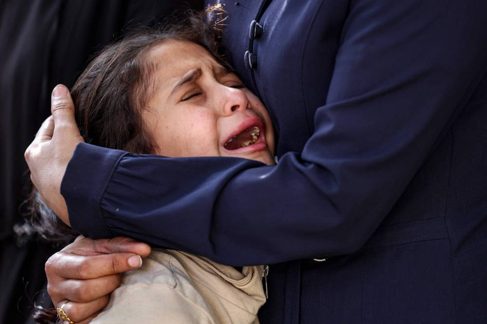 A girl is comforted as she reacts during the funeral of victims killed during overnight Israeli bombardment, at al-Shifa hospital in Gaza City on June 4, 2025. - (Photo by Omar AL-QATTAA / AFP)