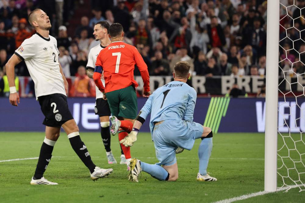 Portugal's forward Cristiano Ronaldo (C) reacts after scoring his team's second goal past Germany's goalkeeper Marc-Andre Ter Stegen (R) during the UEFA Nations League semi-final football match between Germany and Portugal in Munich, southern Germany on June 4, 2025. (Photo by Alexandra BEIER / AFP)