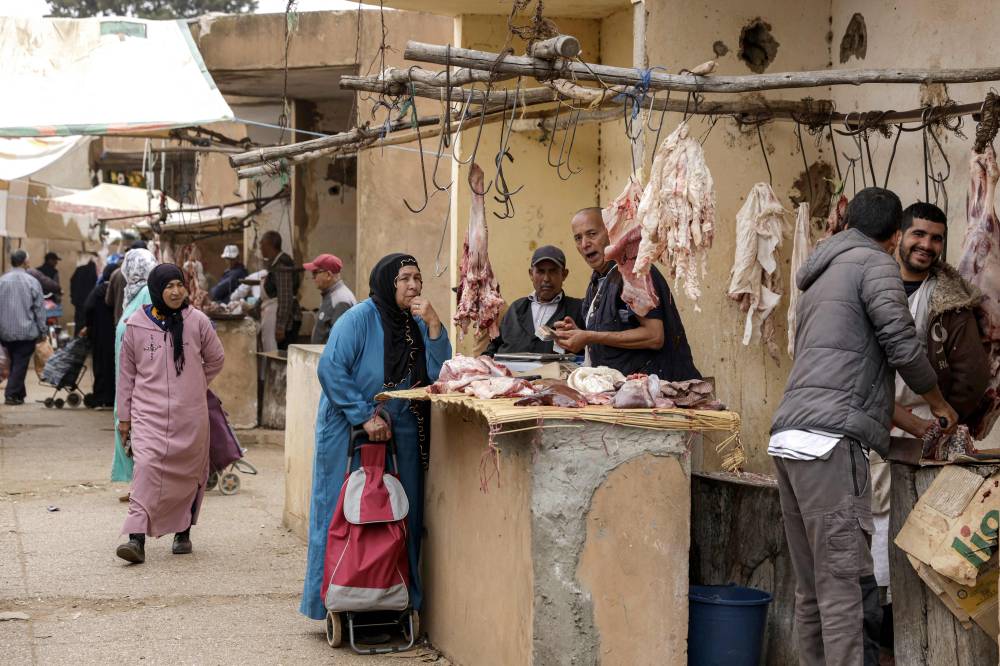 A woman shops for cuts of meat from a butcher at the weekly market in Khemisset in the Rabat region, about 100 kilometres east of the Moroccan capital, on June 3, 2025 amidst preparations ahead of Eid al-Adha, the Muslim feast of sacrifice. - (Photo by ABDEL MAJID BZIOUAT / AFP)