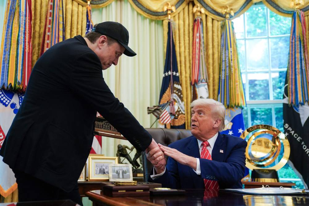 US President Donald Trump shakes hands with Elon Musk after Trump gifted him with a 