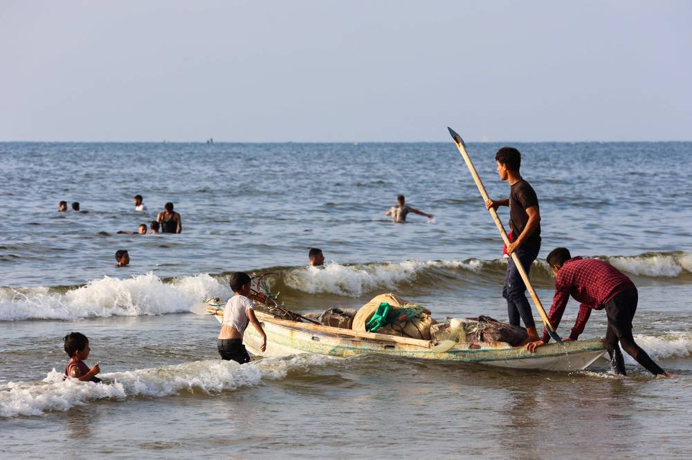 Palestinians gather at the beach in Gaza City to escape the heat and displacement tents. - (Photo by OMAR AL-QATTAA / AFP)