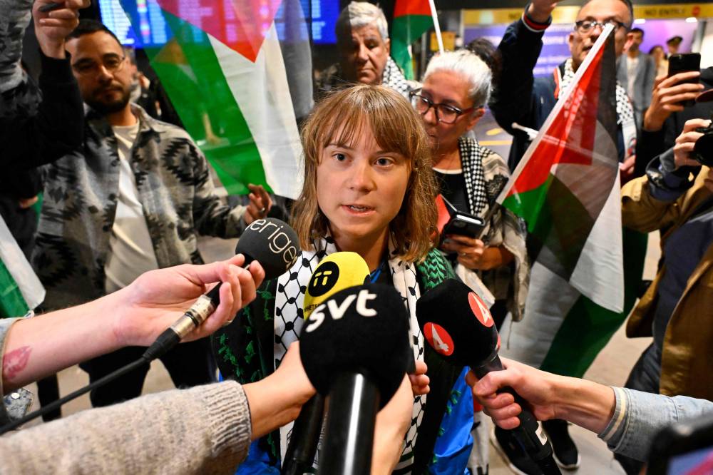 Swedish campaigner Greta Thunberg (C) talks to journalists as she arrives at Stockholm-Arlanda airport, outside Stockholm, on June 10, 2025. - (Photo by ANDERS WIKLUND / TT NEWS AGENCY / AFP)
