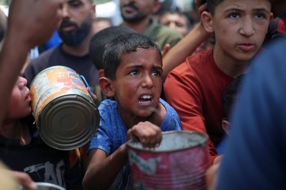 Palestinian children wait for food at a distribution point in Nuseirat, in the central Gaza Strip, on June 11, 2025. (Photo by Eyad BABA / AFP)
