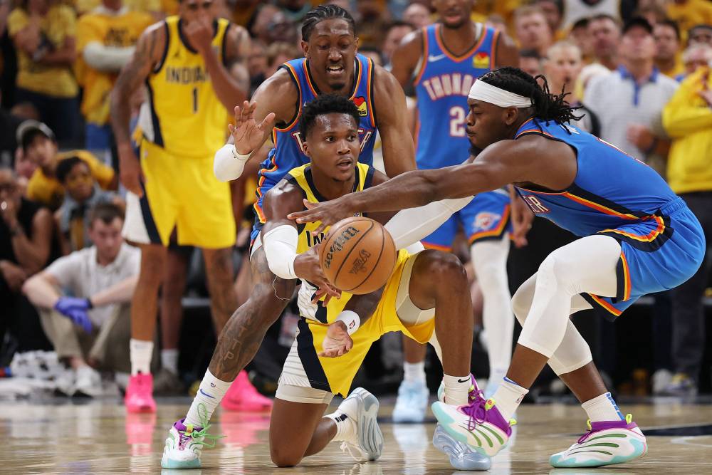 Bennedict Mathurin #00 of the Indiana Pacers passes the ball between Jalen Williams #8 and Luguentz Dort #5 of the Oklahoma City Thunder during the fourth quarter in Game Three of the 2025 NBA Finals at Gainbridge Fieldhouse on June 11, 2025 in Indianapolis, Indiana. Photo by Dylan Buell/Getty Images via AFP