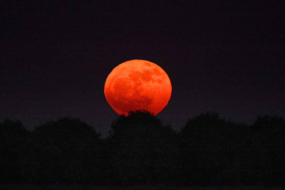 This picture taken from the southern Kibbutz of Afar Aza shows the full moon, known as the 'Strawberry Moon' rising on June 11, 2025. (Photo by Jack GUEZ / AFP)