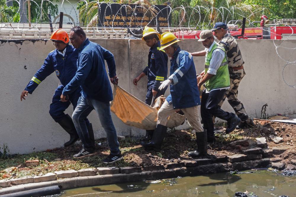 Firefighters carry a victim's body after the Air India flight 171 crashed in a residential area near the airport in Ahmedabad on June 12, 2025. - (Photo by SAM PANTHAKY / AFP)