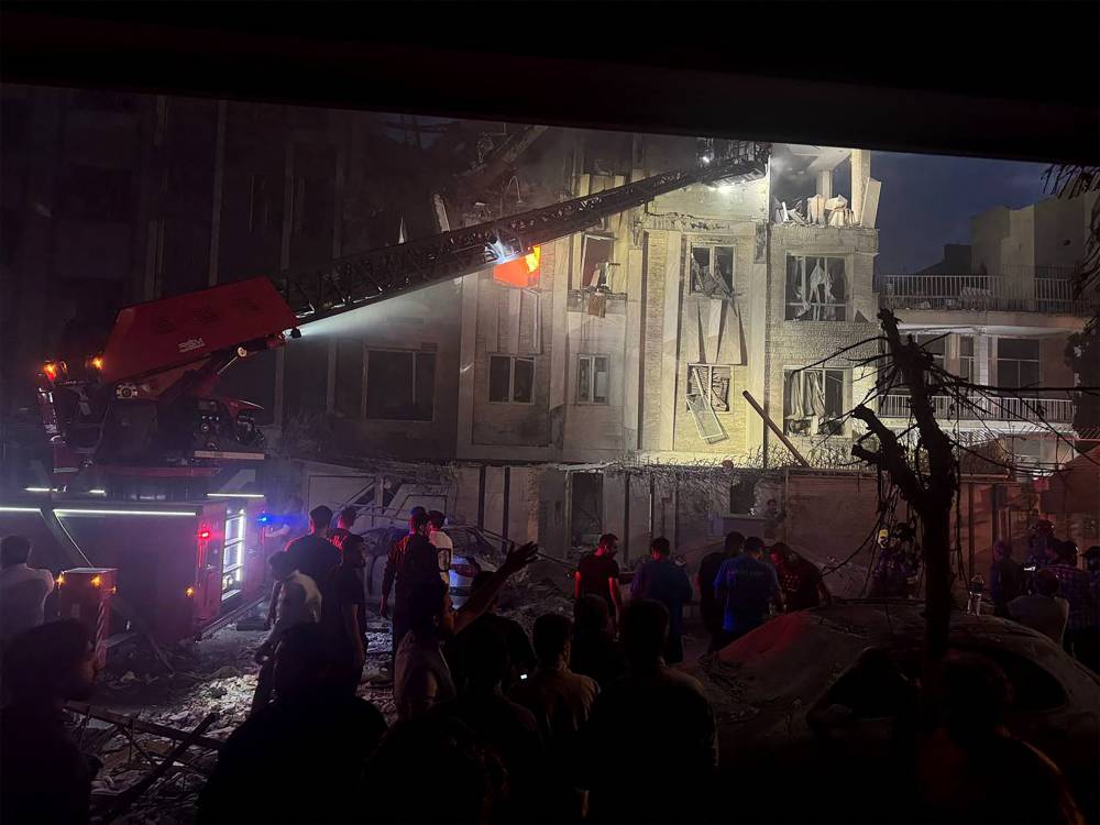 Onlookers and rescue teams in front of a building that caught fire following and Israeli strike on the Iranian capital Tehran early in the morning. Photo by Sepah News/AFP