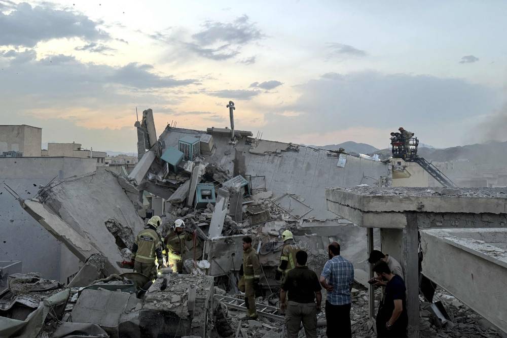 People and first-responders gather atop a building a that was hit by an Israeli strike in Tehran on June 13, 2025. Israel hit about 100 targets in Iran on June 13, including nuclear facilities and military command centres and killing senior figures including the armed forces chief and top nuclear scientists. (Photo by MEGHDAD MADADI / TASNIM NEWS / AFP)