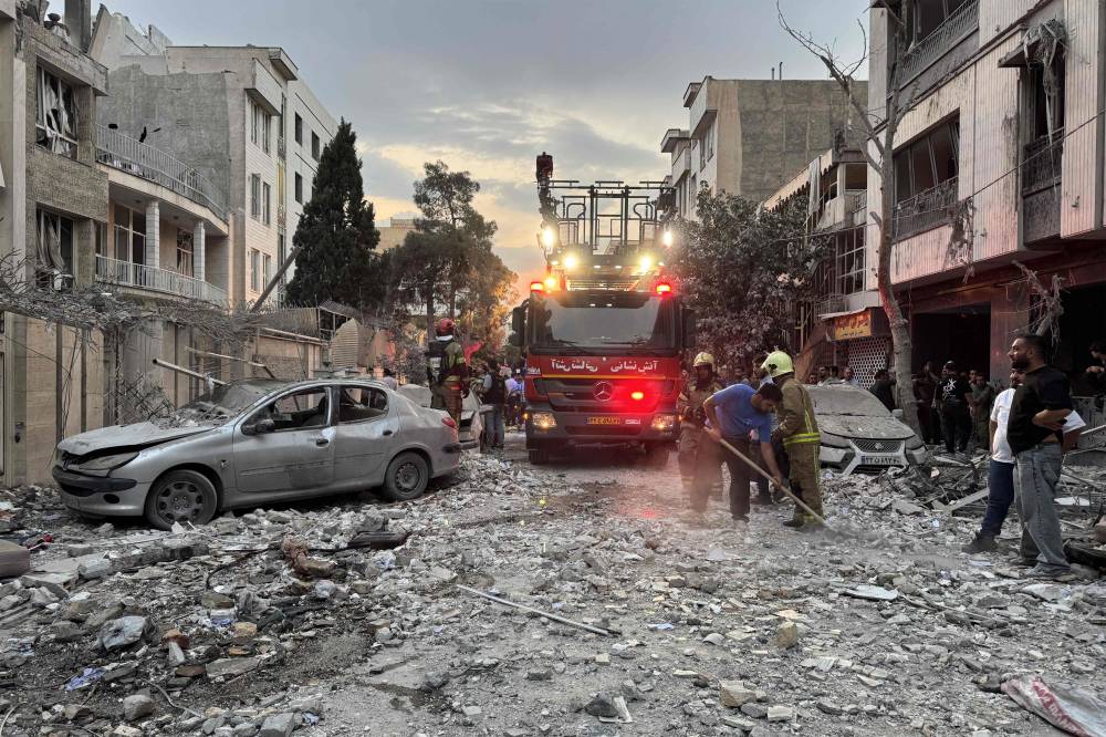 First-responders gather outside a that was hit by an Israeli strike in Tehran on June 13, 2025. Israel hit about 100 targets in Iran on June 13, including nuclear facilities and military command centres and killing senior figures including the armed forces chief and top nuclear scientists. - (Photo by MEGHDAD MADADI / TASNIM NEWS / AFP)