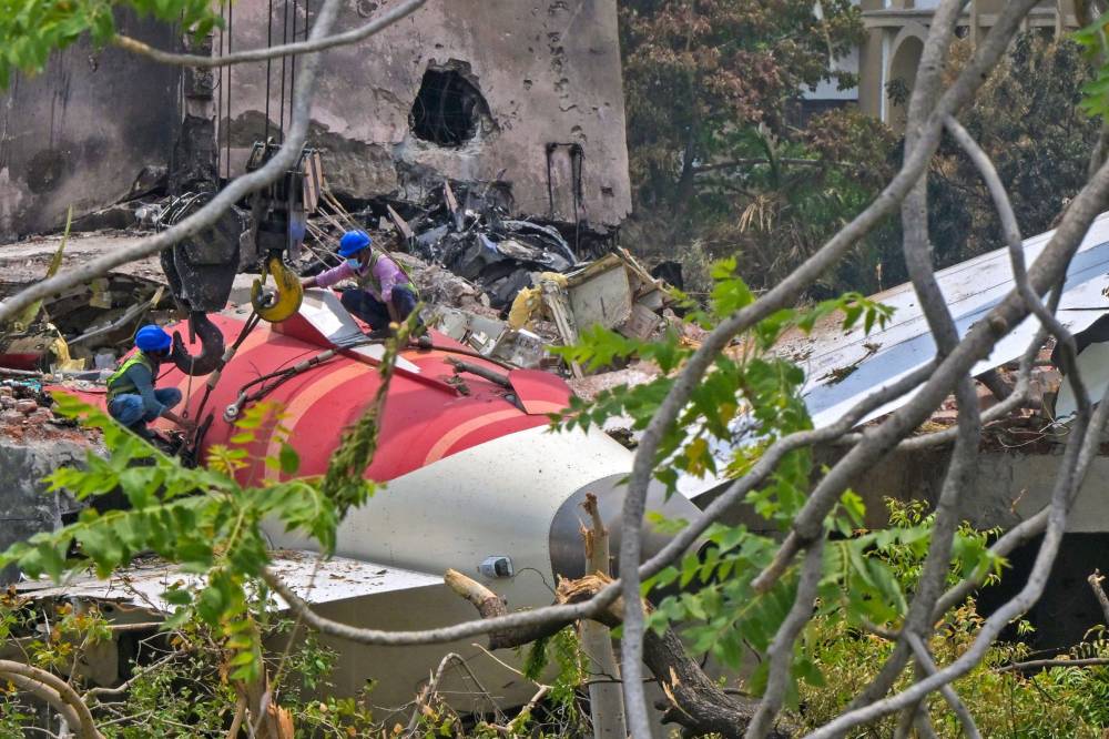 Workers removing aeroplane's tail from the wreckage after the June 12 Air India flight 171 crash, is pictured in a residential area near the airport in Ahmedabad on June 14, 2025. Investigators recovered a black box recorder on June 13 from the crash site of a London-bound passenger jet that ploughed into a residential area of India's Ahmedabad city, killing at least 265 people on board and on the ground. (Photo by DIBYANGSHU SARKAR / AFP)