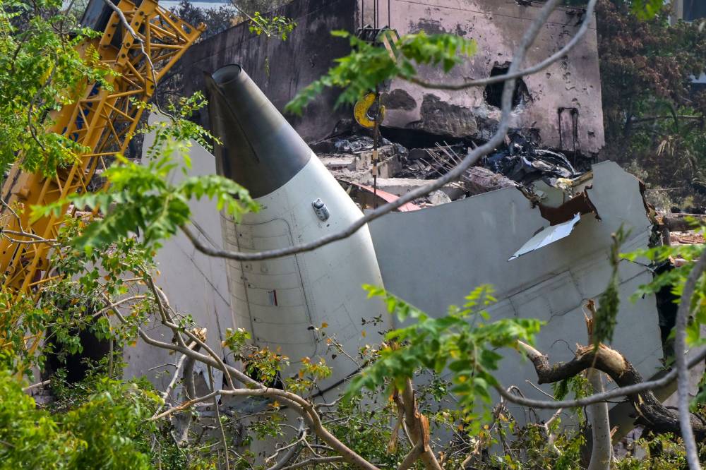 A crane removing aeroplane's tail from the wreckage after the June 12 Air India flight 171 crash, is pictured in a residential area near the airport in Ahmedabad on June 14, 2025. Investigators recovered a black box recorder on June 13 from the crash site of a London-bound passenger jet that ploughed into a residential area of India's Ahmedabad city, killing at least 265 people on board and on the ground. (Photo by DIBYANGSHU SARKAR / AFP)