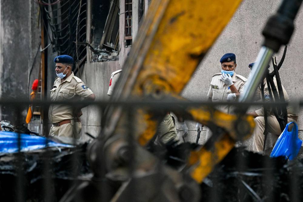 Police personnel inspect the crash site of Air India flight 171 at a residential area near the airport in Ahmedabad on June 15, 2025. The death toll from the fiery crash of a London-bound passenger jet in an Indian city climbed to 279 on June 14, as officials sought to match the DNA of victims with their grieving relatives. (Photo by Punit PARANJPE / AFP)
