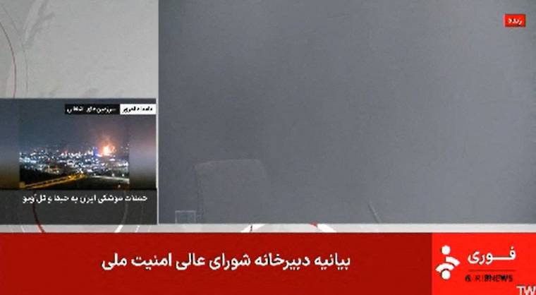 This image grab taken from footage broadcast by Iran's IRINN news on June 16, 2025, shows a news reporting room filled with smoke after the presenter left following an explosion. The Islamic Republic of Iran Broadcasting building was struck in an Israeli attack on June 16, cutting live coverage immediately. - (Photo by IRINN / AFP)
