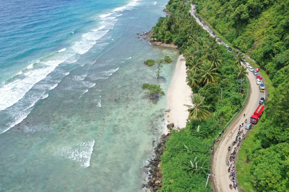 This aerial picture shows motorists waiting in a queue to pass through a section of road affected by a landslide caused by a 6.2 magnitude earthquake in Majene, West Sulawesi on Jan 19, 2021. - (Photo by ADEK BERRY / AFP)