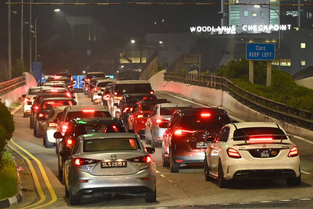 Vehicles form a long queue to enter the Woodlands Checkpoint in Singapore early on April 1, 2022, before crossing the causeway to Malaysia's southern Johor state, as both countries reopen its borders to all fully vaccinated travellers. - (Photo by ROSLAN RAHMAN / AFP)