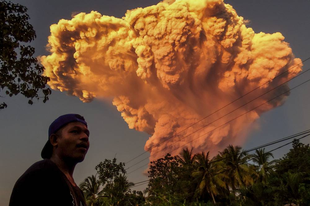 A villager watches the eruption of Mount Lewotobi Laki-Laki as seen from Talibura village in Sikka, East Nusa Tenggara, on June 17, 2025. A volcano in eastern Indonesia spewed a colossal ash tower into the sky on June 17, authorities said, after they raised its alert level to the highest of a four-tiered system. (Photo by AFP)