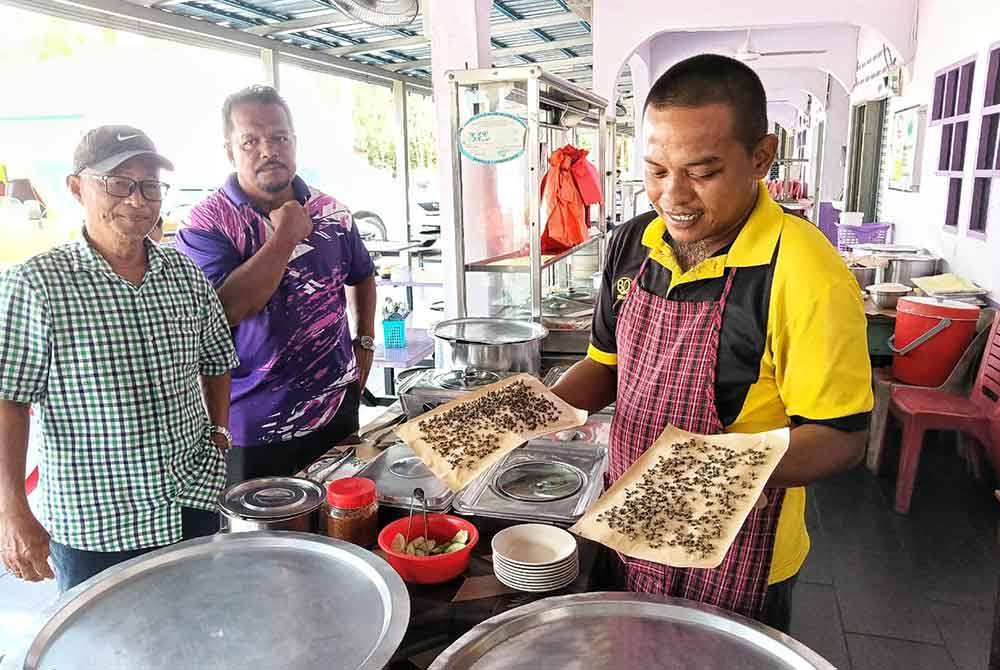 Roslan (left) observes a vendor at the Simpang Bekoh Food Court who is forced to use fly traps.