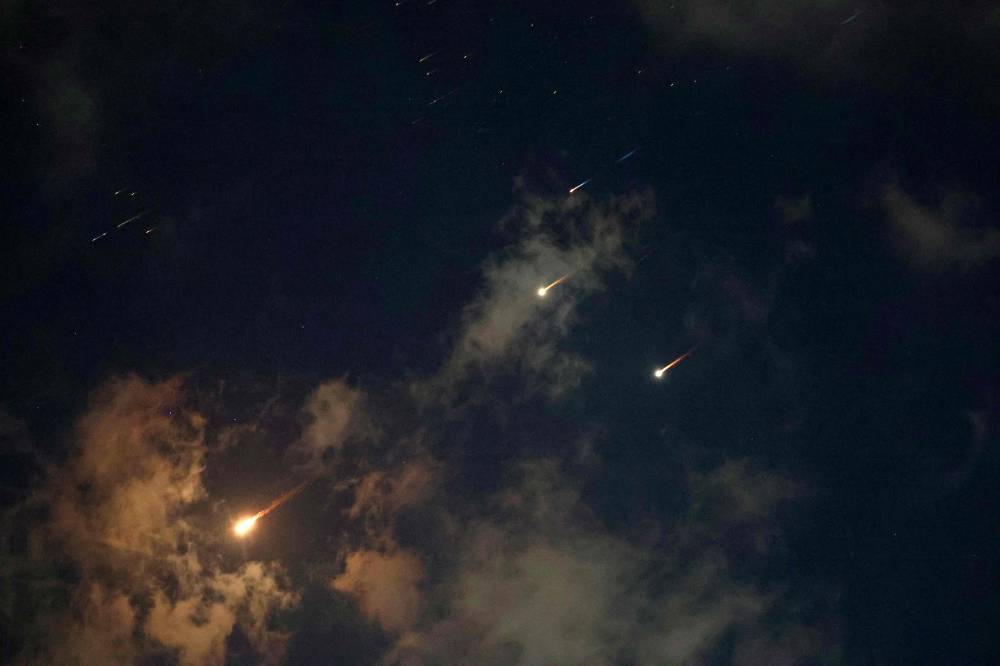 Rocket trails are seen in the sky above the Israeli coastal city of Netanya amid a fresh barrage of Iranian missile attacks on June 17, 2025. (Photo by JACK GUEZ / AFP)