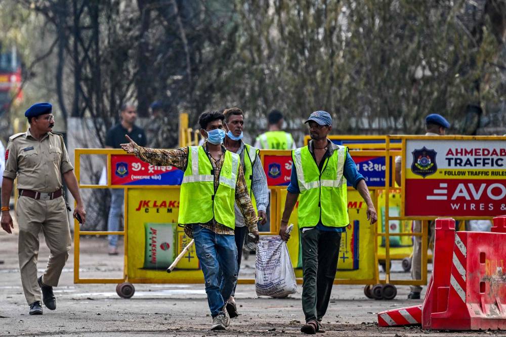 Workers clear debris from the Air India flight crash site at a residential area near the airport in Ahmedabad on June 15, 2025. The death toll from the fiery crash of a London-bound passenger jet in an Indian city climbed to 279 on June 14, as officials sought to match the DNA of victims with their grieving relatives. (Photo by Punit PARANJPE / AFP)