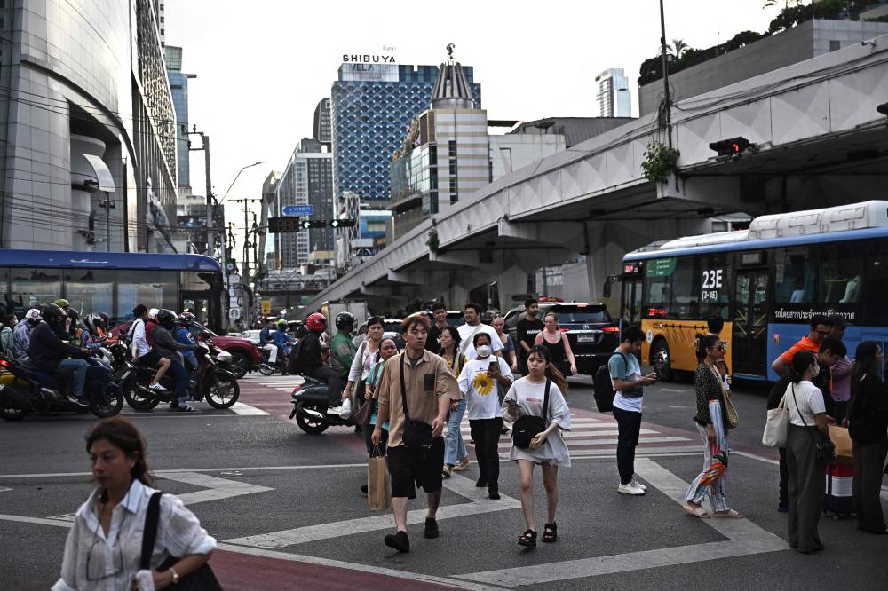 People walk across a pedestrian crossing in Bangkok on June 16, 2025. (Photo by Lillian SUWANRUMPHA / AFP)