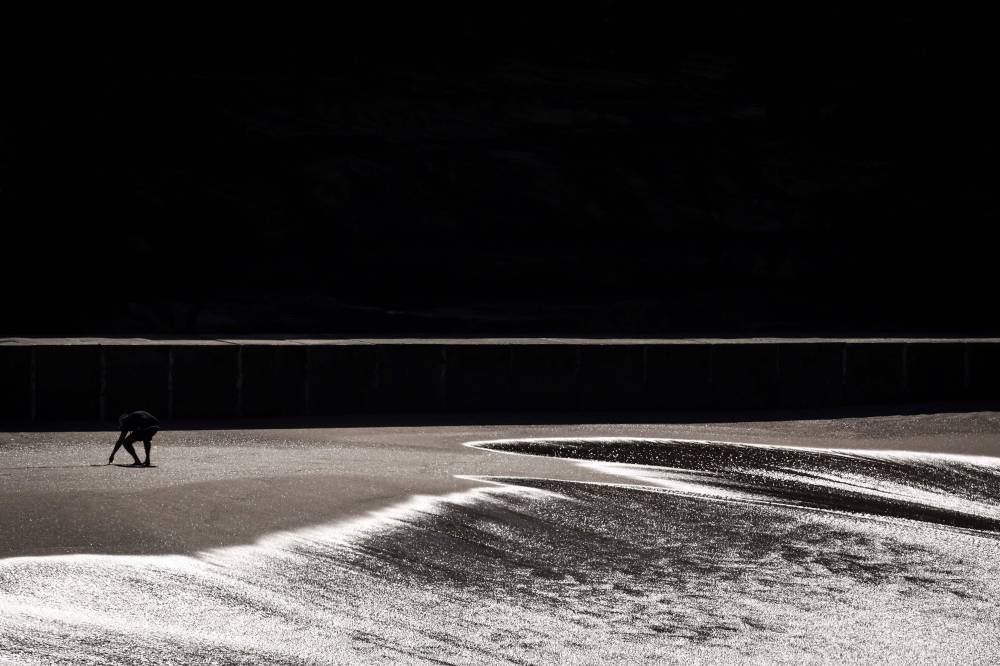 A man digs a hole in the sand as he walks along Bronte Beach on a winter’s day in Sydney on June 19, 2025. (Photo by DAVID GRAY / AFP)