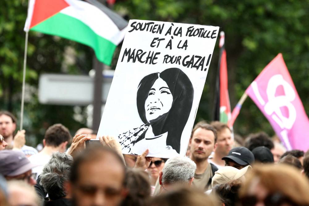 A protester holds a placard depicting French-Palestinian lawyer and member of European Parliament for La France Insoumise (LFI) party Rima Hassan during a pro-Palestinian demonstration called by several French unions in Paris on June 14, 2025. French Democratic Confederation of Labour trade union (CFDT), French trade union General Confederation of Labour (CGT), French National Union of Autonomous Trade Unions (Unsa) Unsa, French group of trade unions Union syndicale Solidaires (SUD) and French trade union 