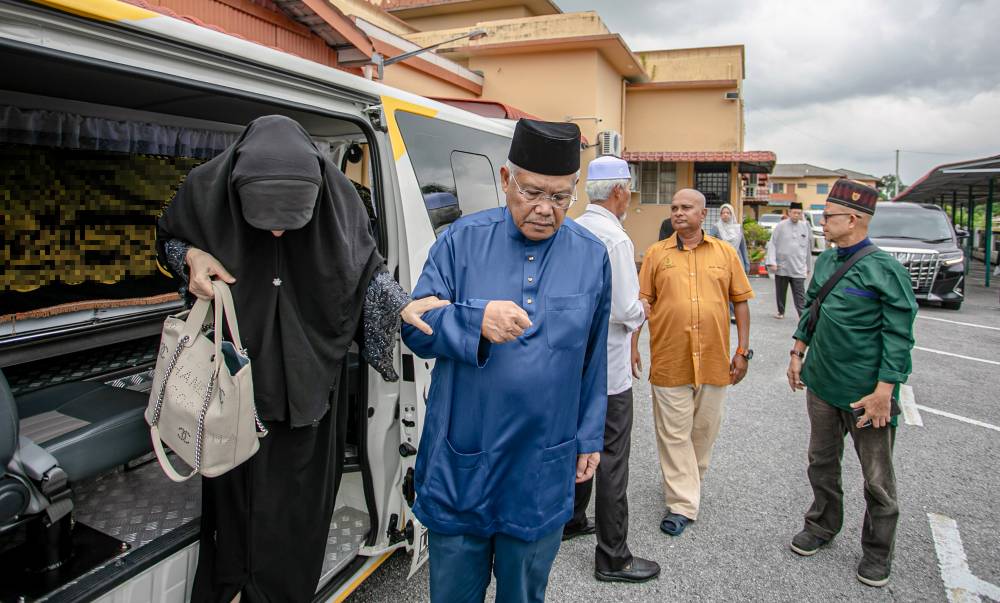 Family members, including Larut MP Datuk Seri Hamzah Zainudin and his wife, gather as investigations continue into a fatal house fire in Ipoh that resulted in the death of Hamzah's mother-in-law. - Bernama photo