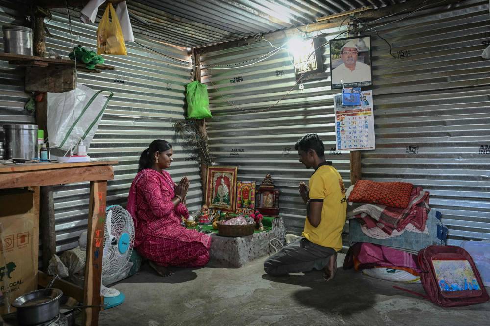 In this photograph taken on May 4, 2025, Jyoti Thorat (L), a sugarcane worker who was married as a child bride, prays with her husband, Ravindra, in their home at Kathoda village in Beed district of India's state of Maharashtra. - (Photo by INDRANIL MUKHERJEE / AFP)
